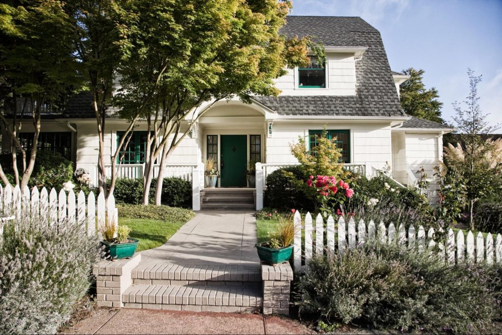 Home with a white picket fence and shrubbery. 