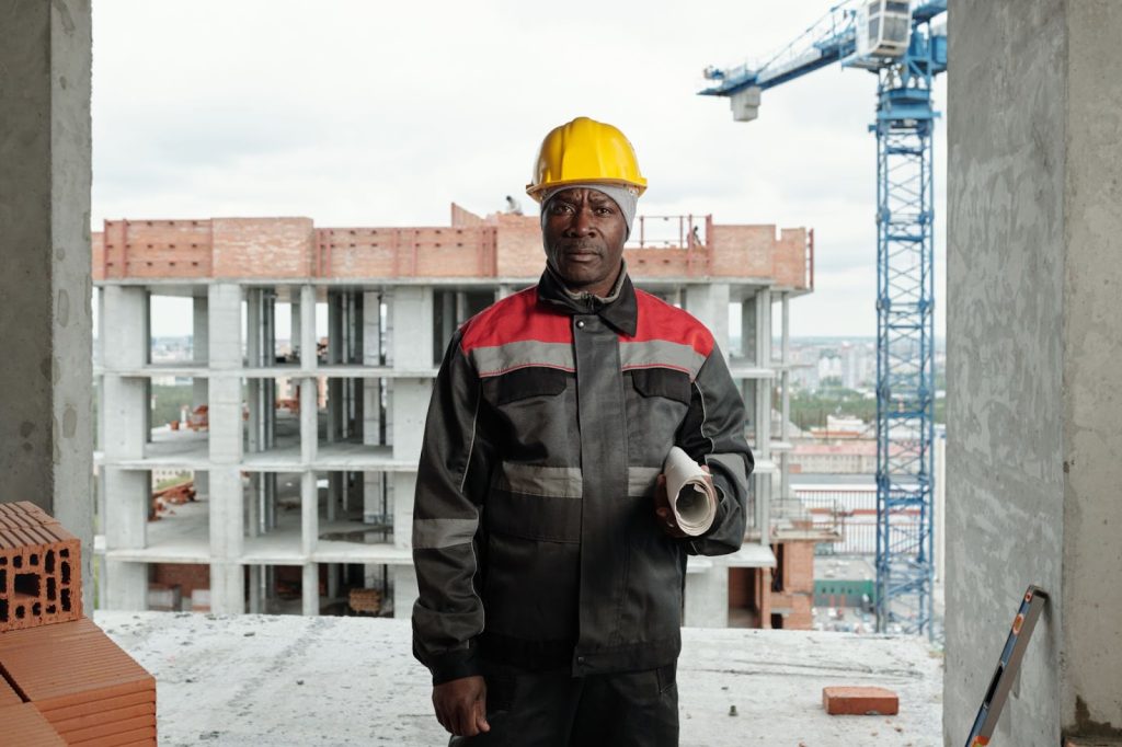 A professional construction contractor holding a rolled blueprint.