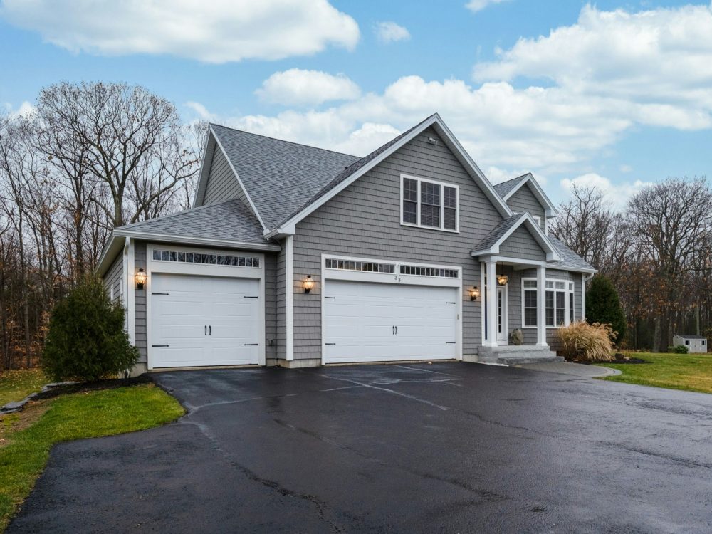 Gray-walled suburban house with white asphalt driveway