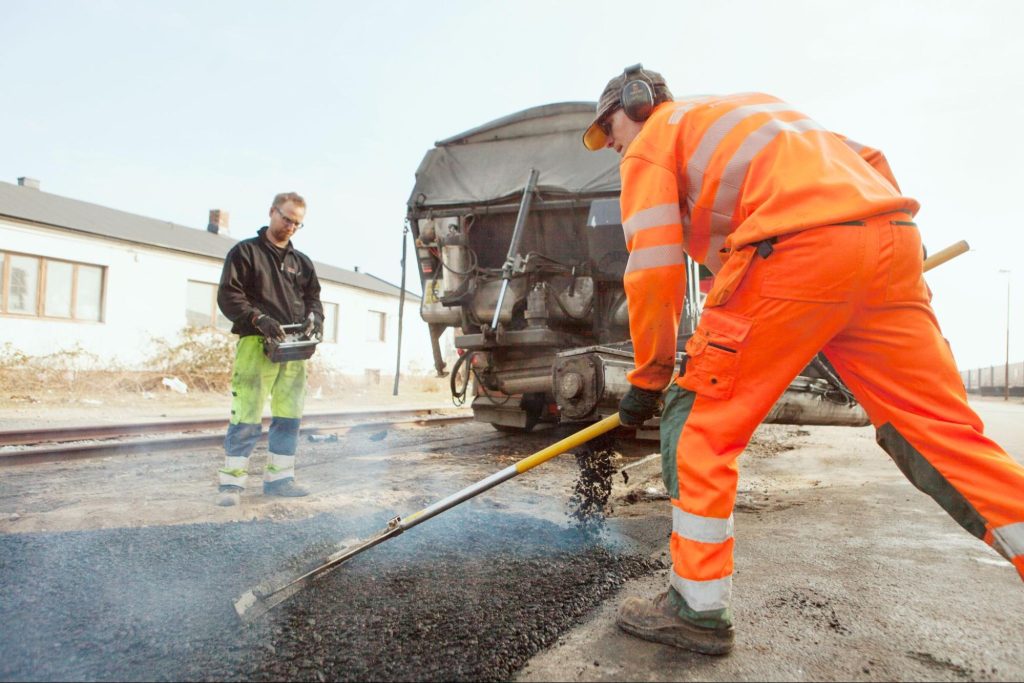 Two road workers asphalt sealing.