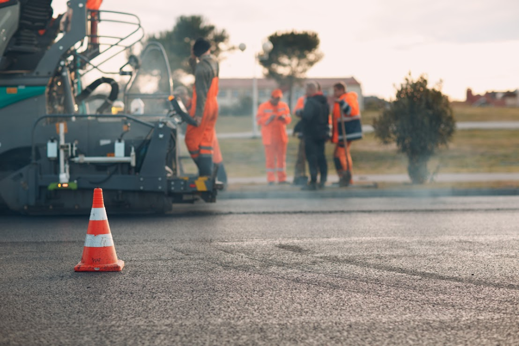A construction team is working on installing asphalt with a paver machine.